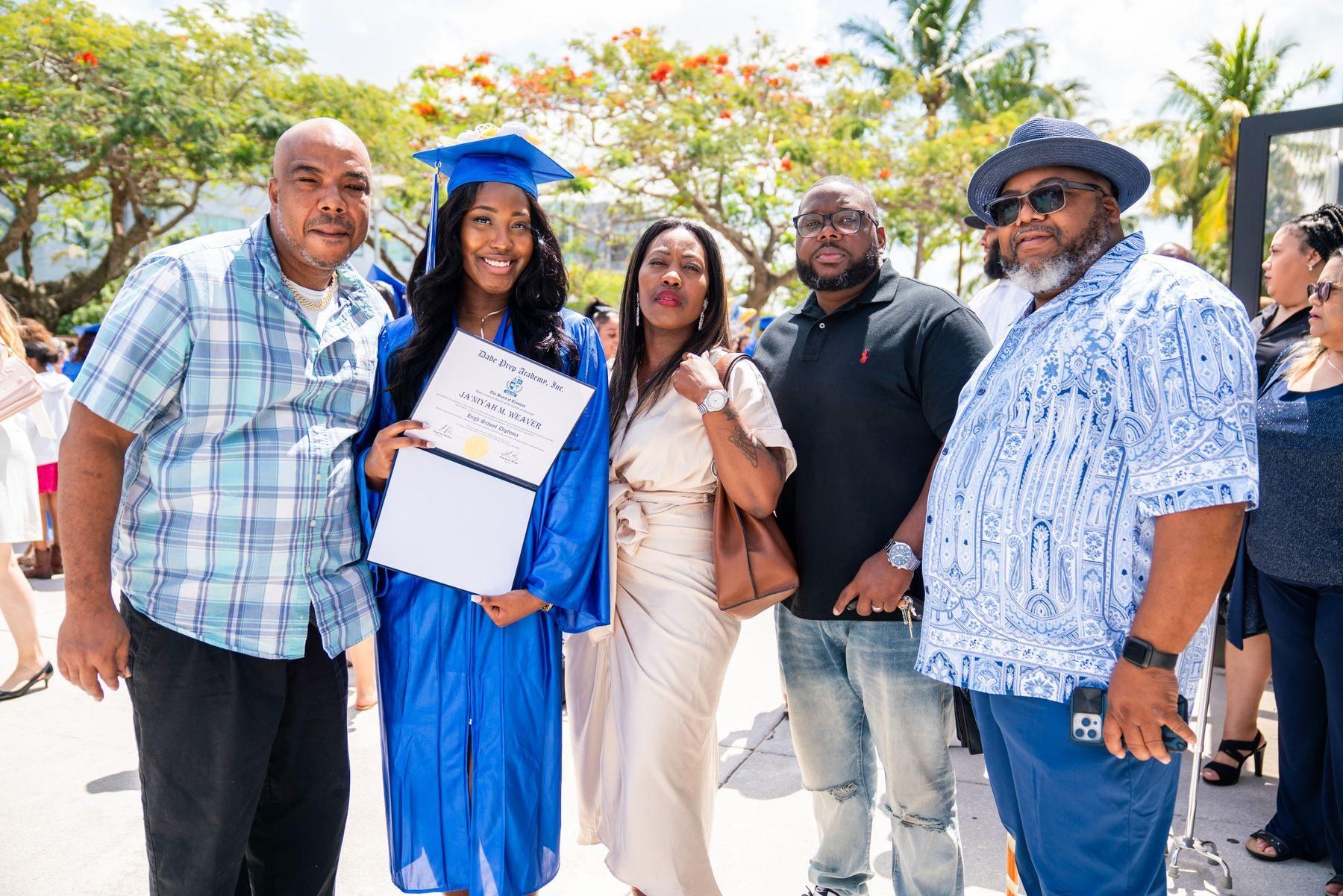 A graduate posing with family members after the ceremony